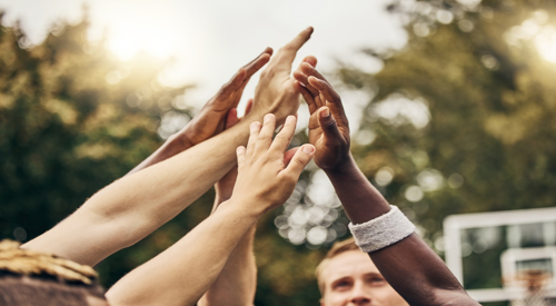 Group of people on a basketball court raising their hands up together